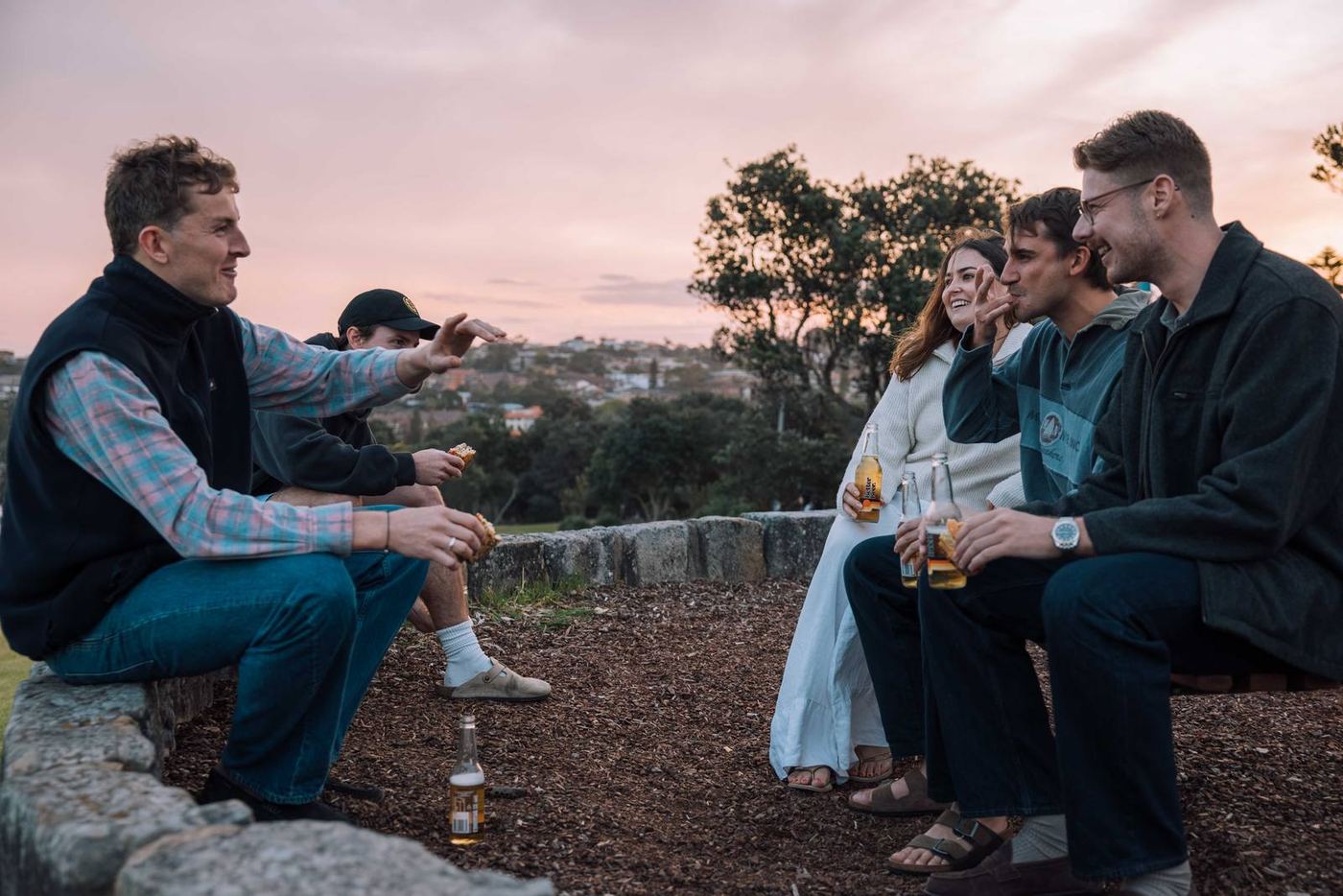 Friends talking over food at sunset on a rocky headland